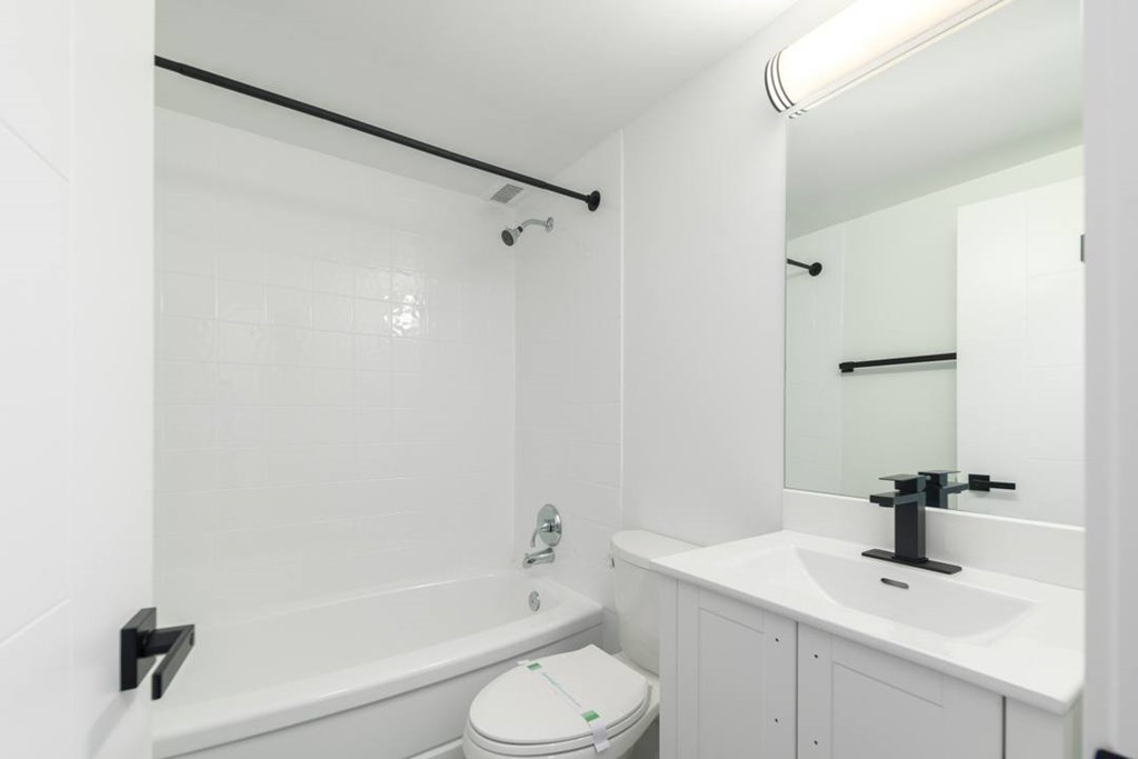 A white bathroom with a toilet, sink, and bathtub.