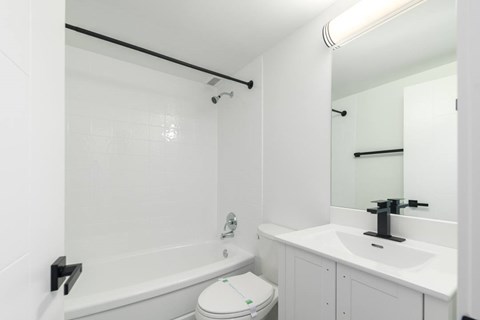 A white bathroom with a toilet, sink, and bathtub.
