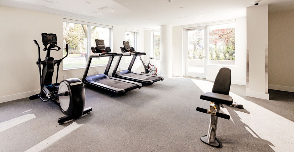 A home gym with a treadmill, elliptical trainer, and stationary bike.