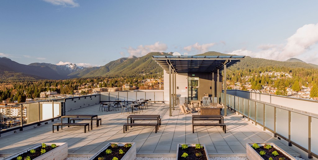 A rooftop patio with a table and chairs overlooking a mountain range.