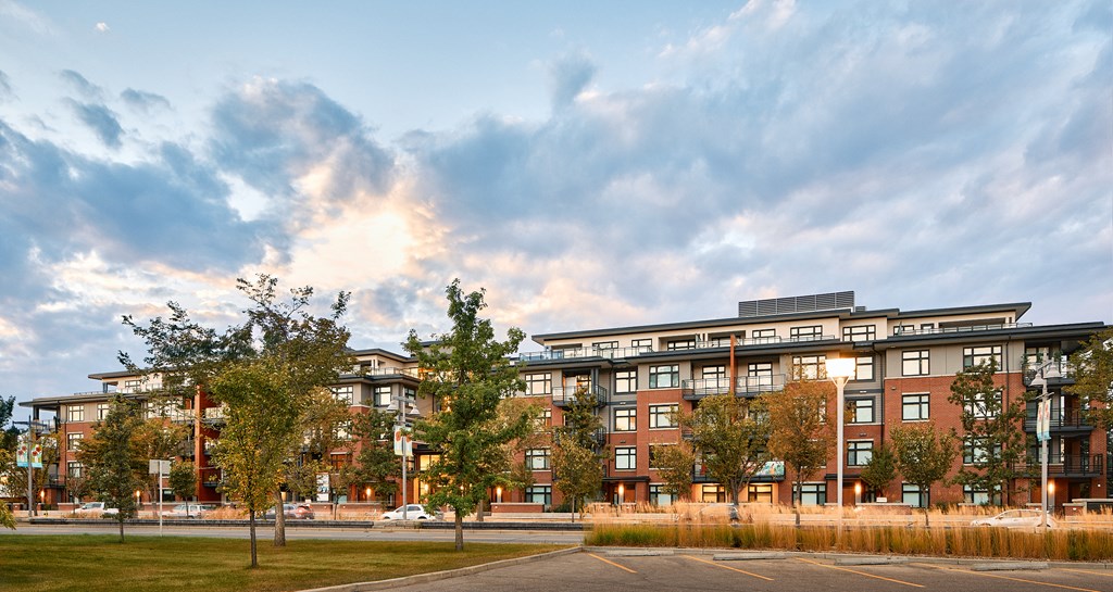 A modern apartment building with a grassy area in front and trees around.