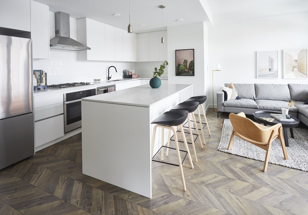 A modern kitchen with a white island and wooden flooring.