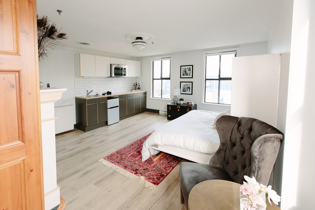 A bedroom with a bed, chair, and a rug.