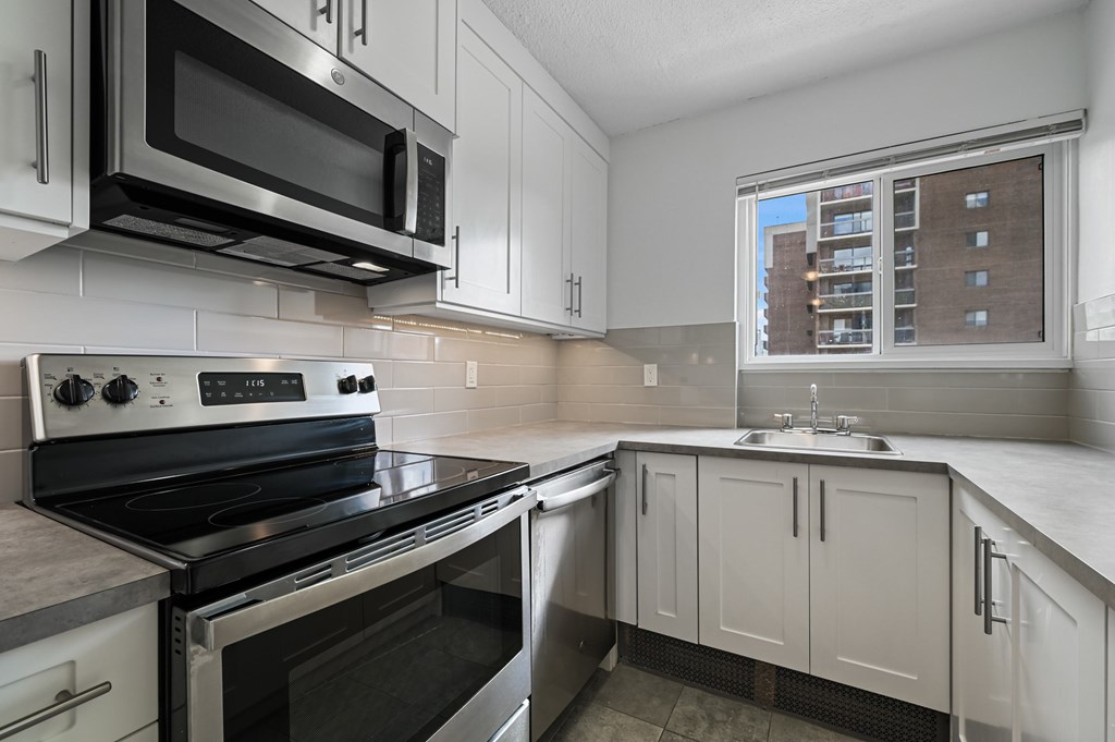 A modern kitchen with white cabinets and stainless steel appliances.