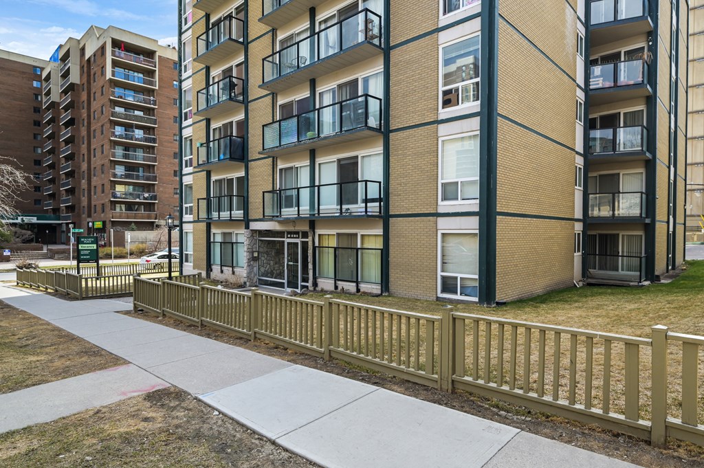 A view of apartment buildings with balconies and a sidewalk.