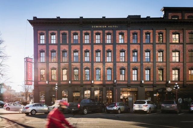 A man in a red jacket is riding a bicycle on a street.