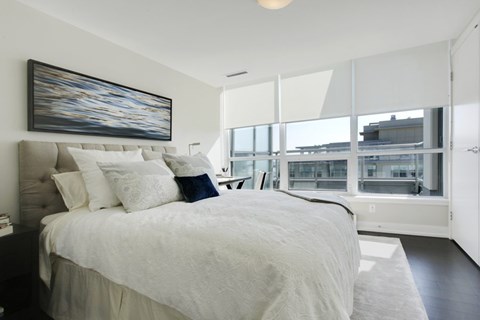 A bedroom with a large bed and a painting on the wall.