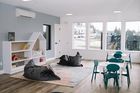 A room with a grey wall and a white shelf with books and toys.