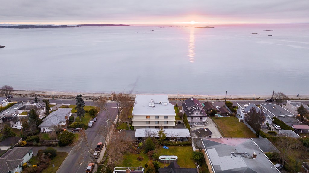 A sunset view of a residential area with houses and a body of water.