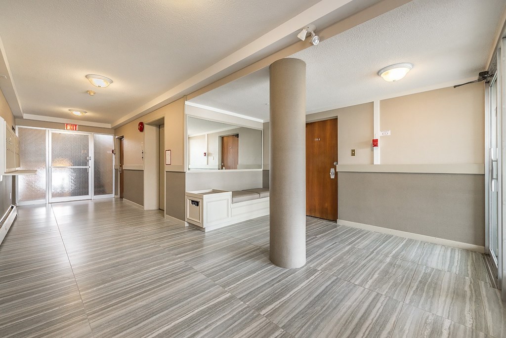 A long hallway with a white ceiling and grey flooring.