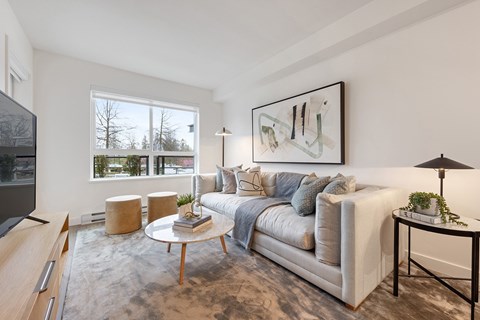 A modern living room with a large window, a white sofa, and a coffee table.