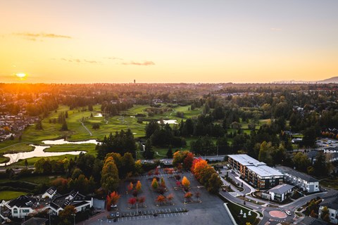A sunset view of a residential area with a parking lot in the foreground.