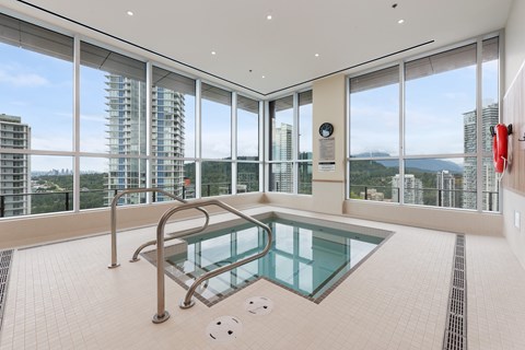 A glass pool in a room with a view of the city.