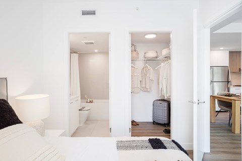A white bedroom with a bed, a desk, and a wardrobe.