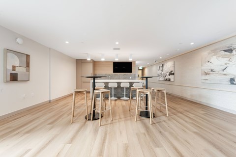 A modern dining room with a wooden floor and a large painting on the wall.