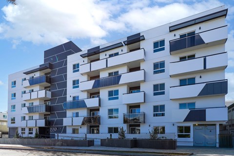 A modern white apartment building with black and blue accents.