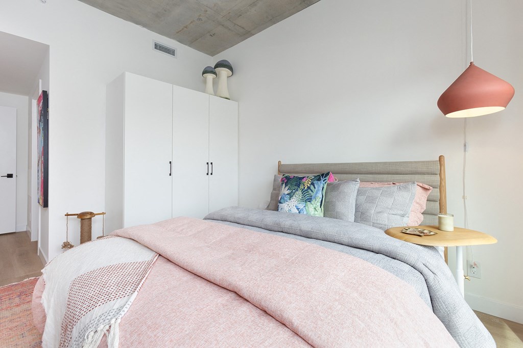 a bedroom with a bed and a pink bedspread and pillows