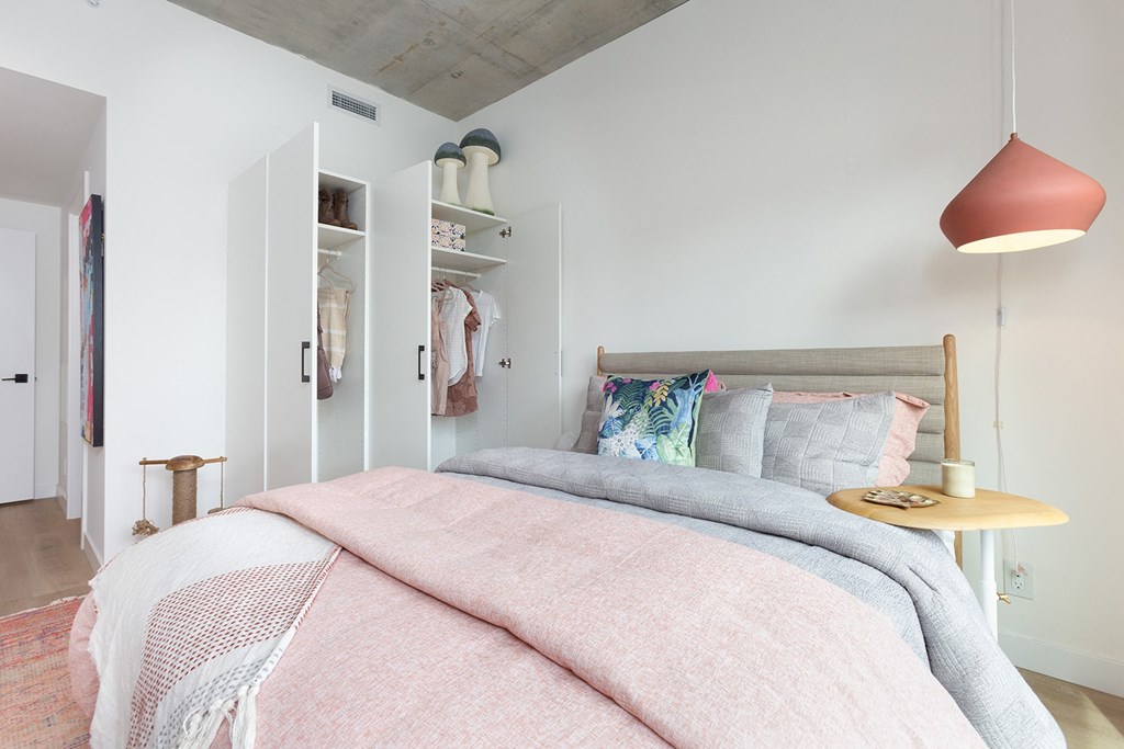 a bedroom with a bed and a pink lamp and a closet