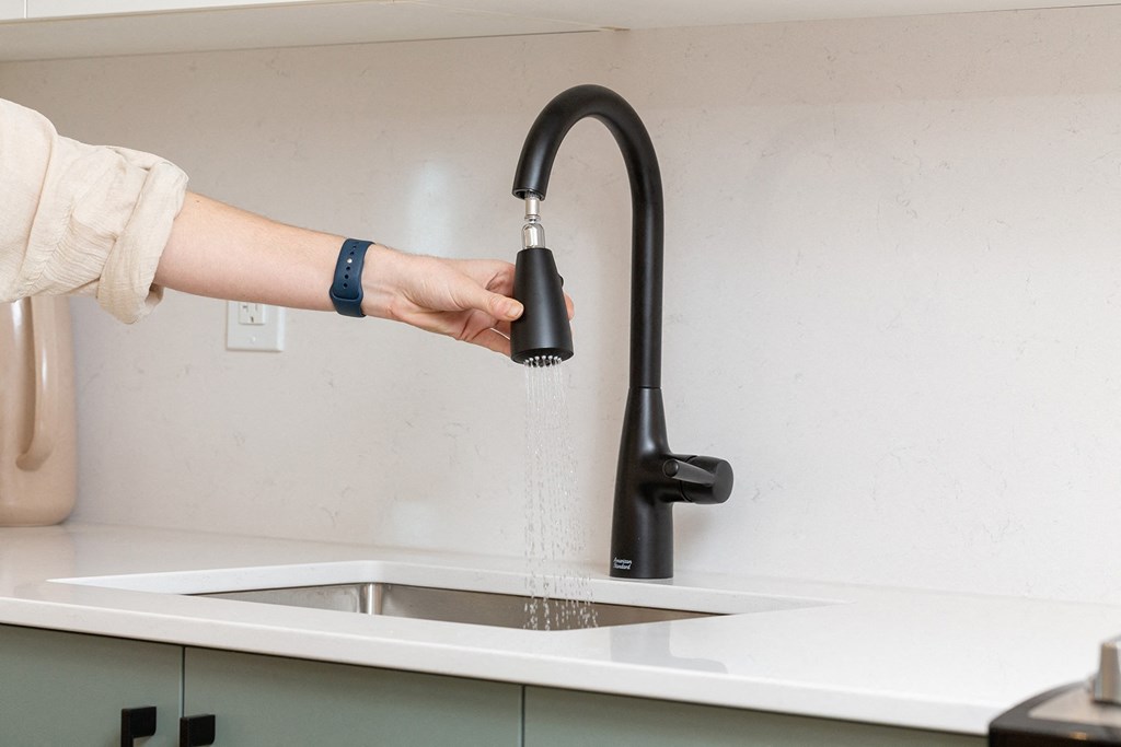 a person pouring water out of a kitchen faucet
