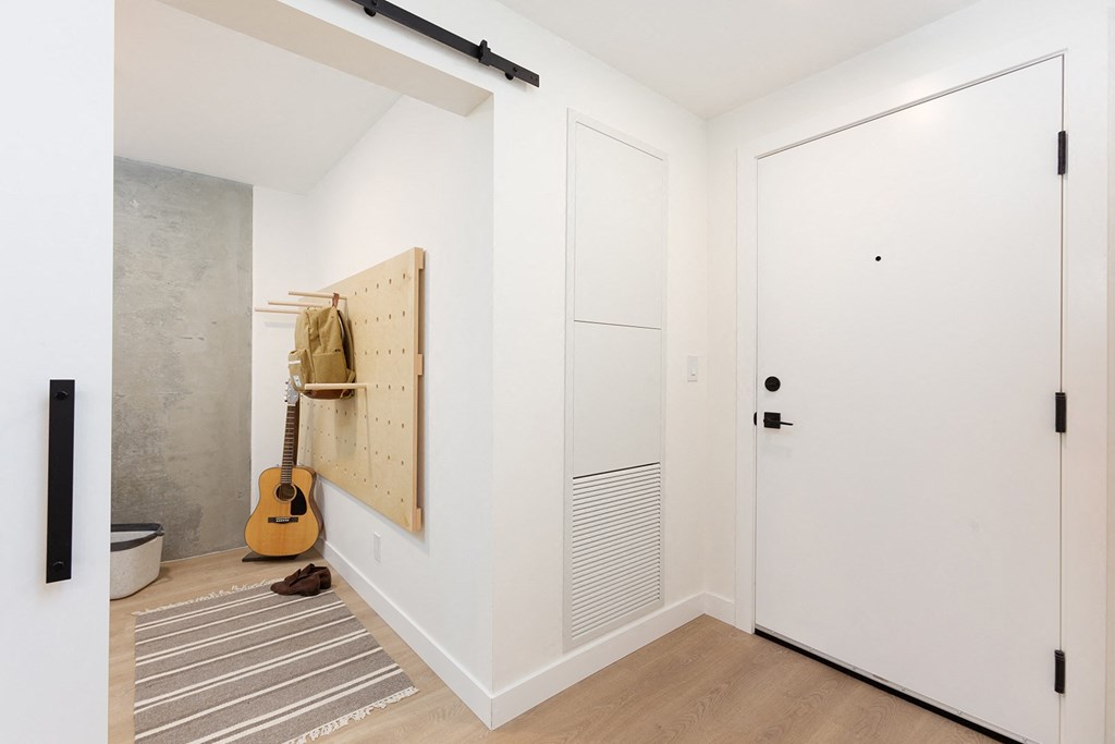 a hallway with a white door and a guitar on the wall