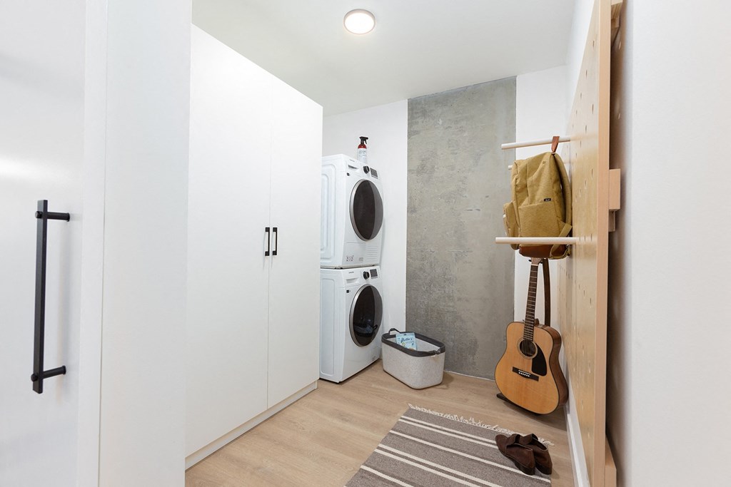 a laundry room with a washing machine and a guitar on the wall