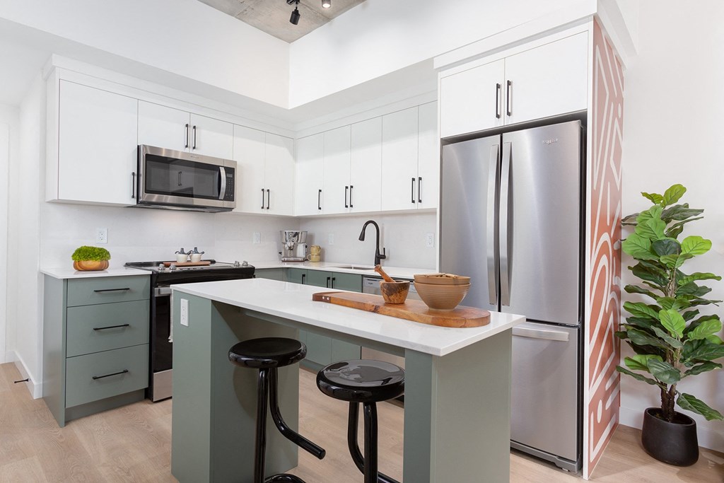 a kitchen with white cabinets and a long island with black stools