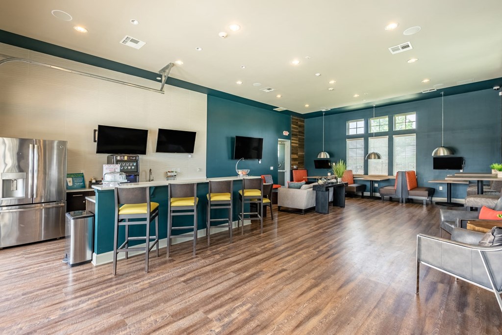 a lounge area with tables and chairs and a refrigerator and tv