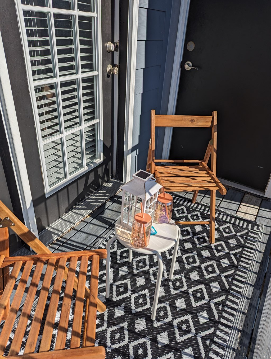 a small porch with two chairs and a table and a door