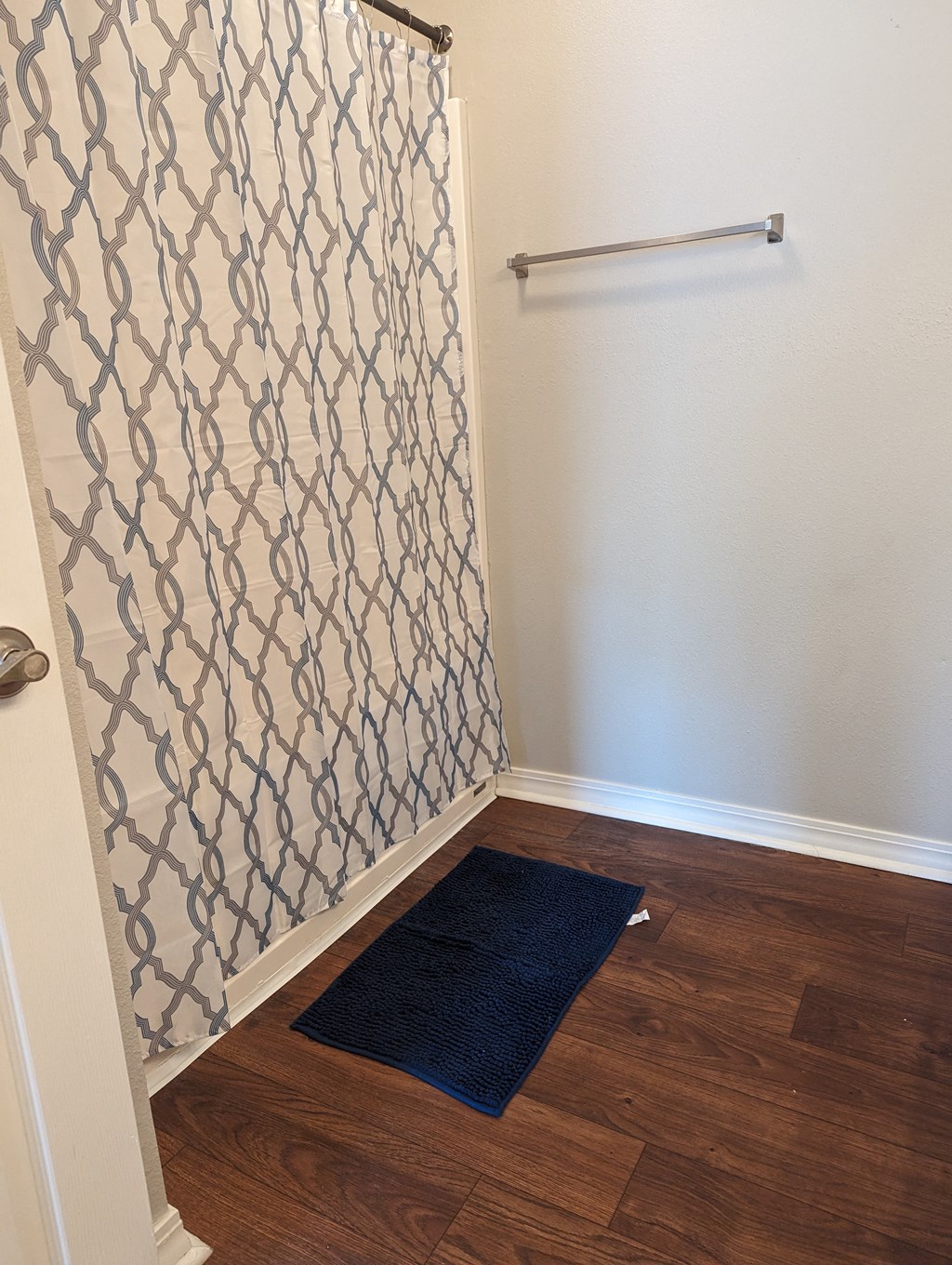 a small bathroom with a shower curtain and a rug on the floor