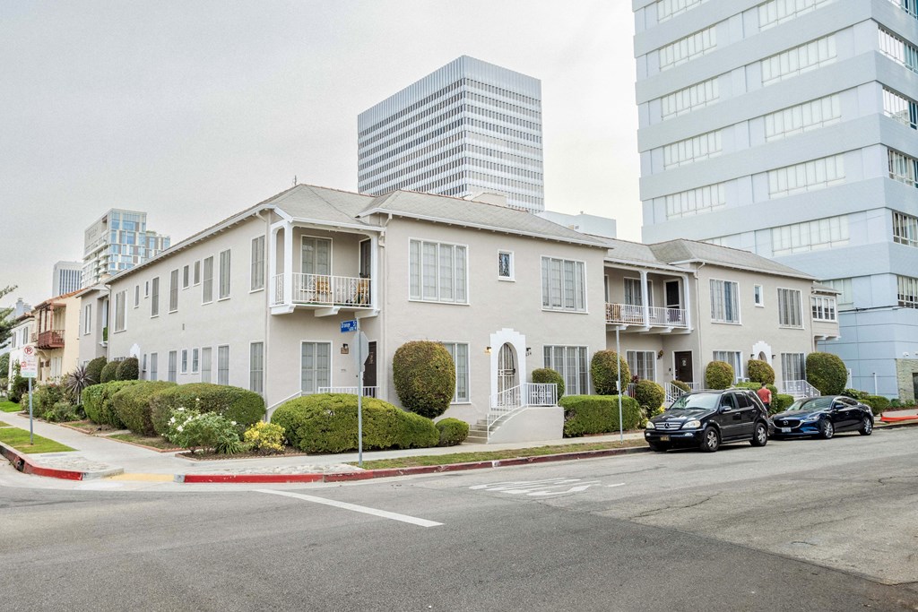 A row of townhouses with cars parked in front.
