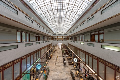 A long, empty hallway with a glass ceiling and rows of windows on both sides.
