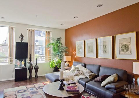 A living room with a black leather couch, a coffee table, and a flat screen TV.