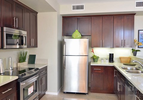 A modern kitchen with a stainless steel refrigerator and wooden cabinets.