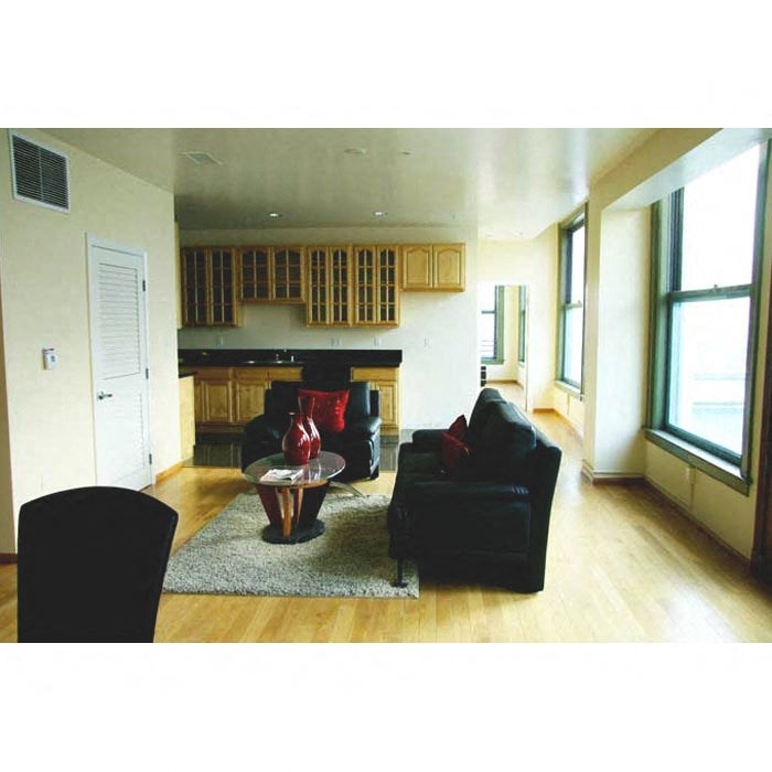 A living room with a black couch and a red vase on a coffee table.