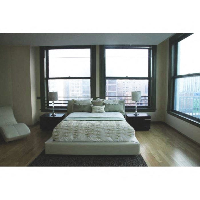 A bedroom with a large bed and a chair.