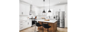 a large white kitchen with stainless steel appliances and a center island