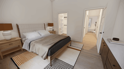 A bedroom with a large bed and a striped rug on the floor.