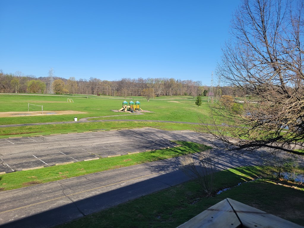 A park with a playground and a paved area.