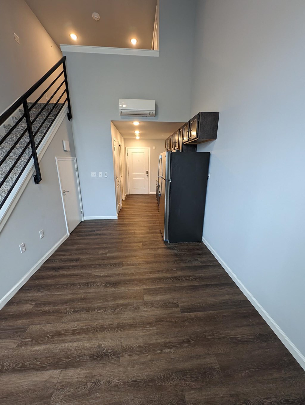 a hallway with wood floors and white walls and a staircase