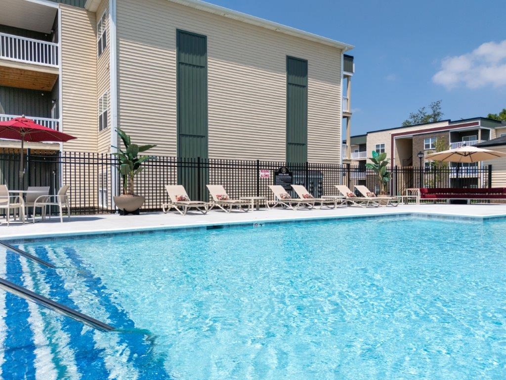 a swimming pool with chairs and a building in the background