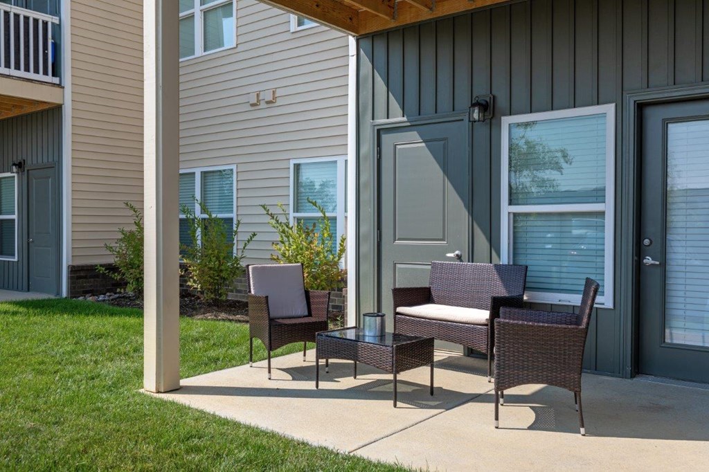a patio with a table and chairs in front of a house