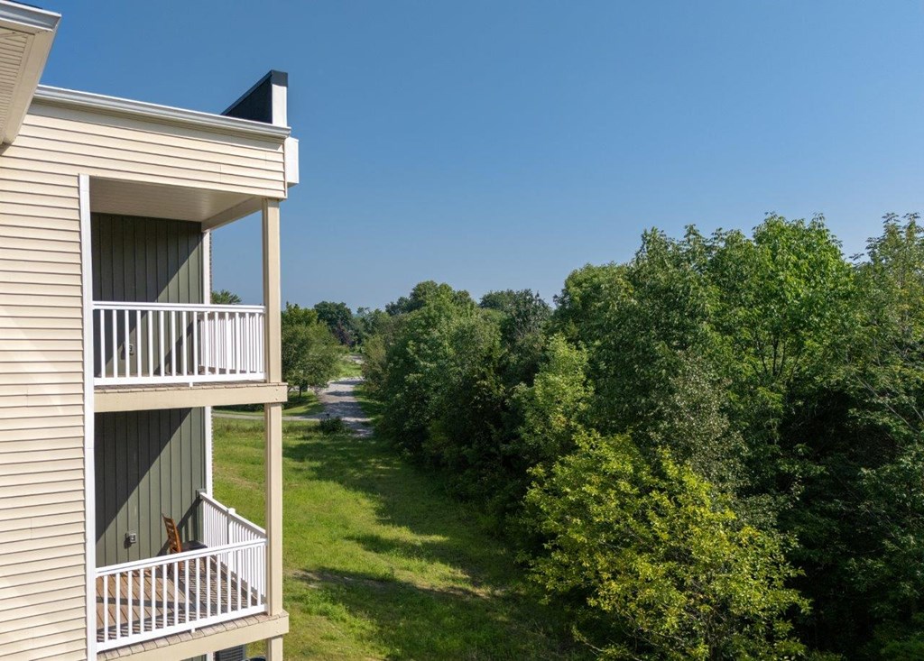 a view from the balcony of a house overlooking a grassy field and trees