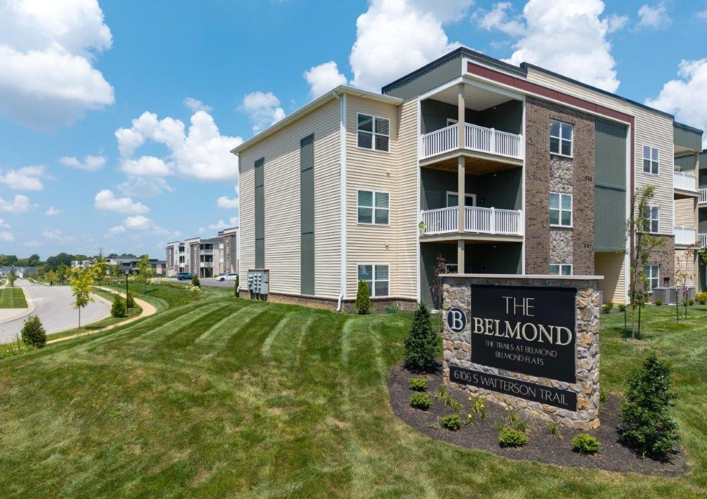 The Belmond apartments are located in a grassy area with a clear blue sky.