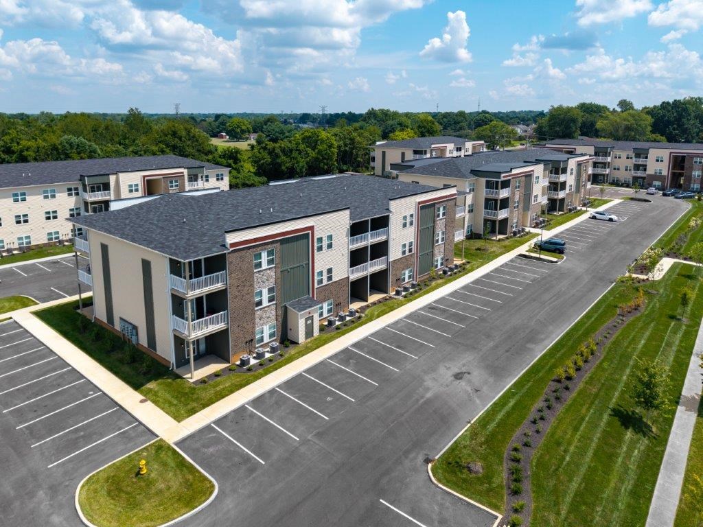 A large apartment complex with a parking lot in front.