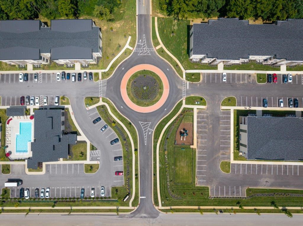 A roundabout with a red circle in the middle and cars parked in the parking lot.