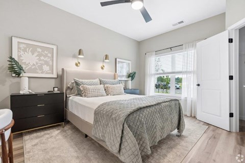 A bedroom with a bed, dresser, and a ceiling fan.