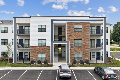 A modern apartment building with a parking lot in front.
