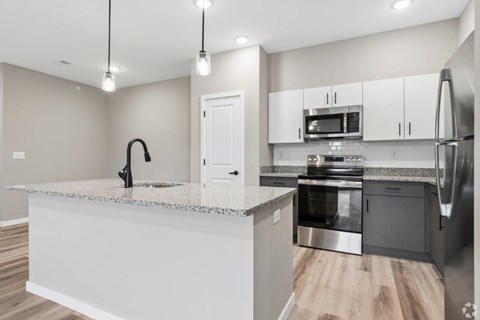 A modern kitchen with a white countertop and stainless steel appliances.