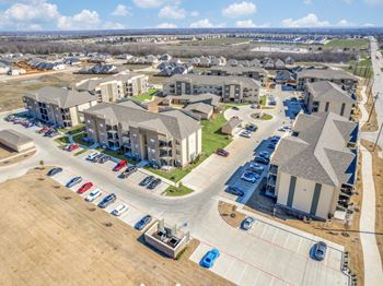 A large apartment complex with a parking lot in front.