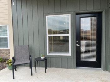 a patio with a chair and a table in front of a door